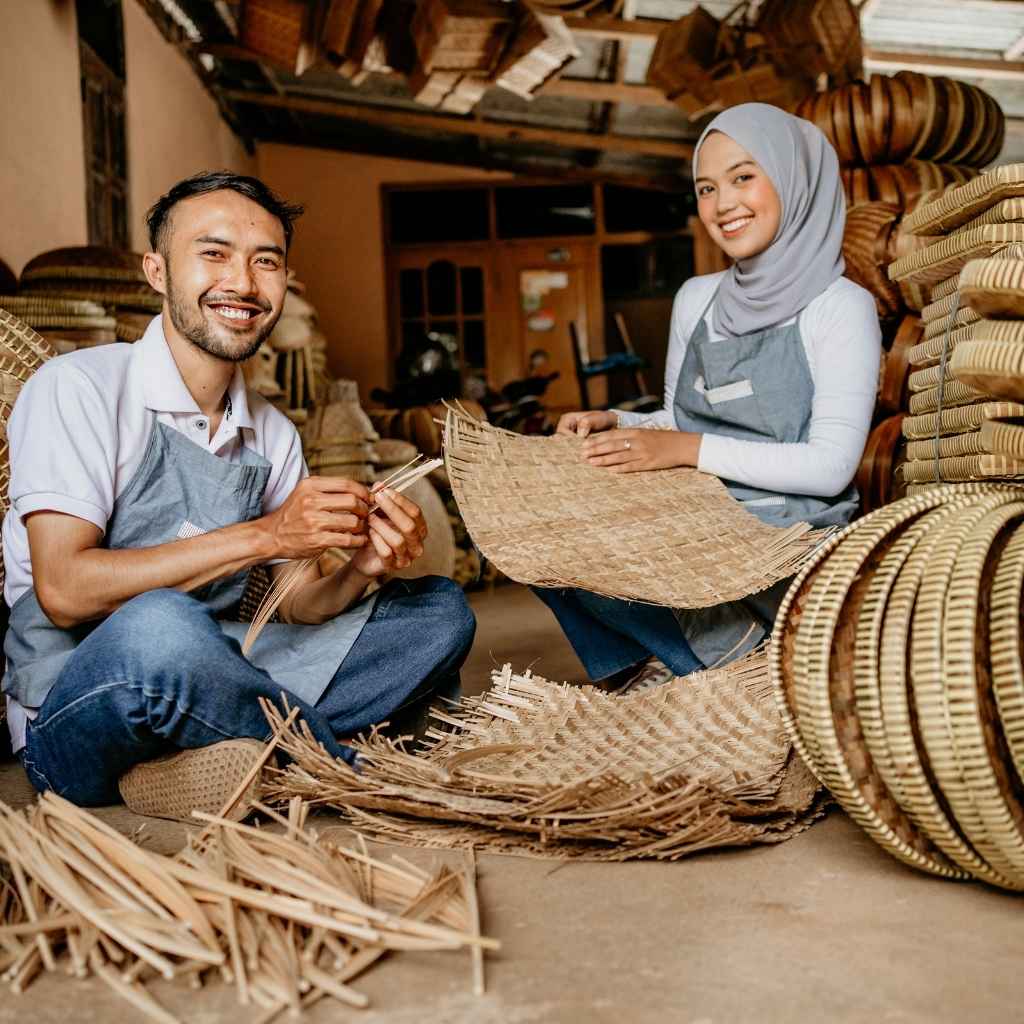 Two people working with woven materials in a workshop setting.