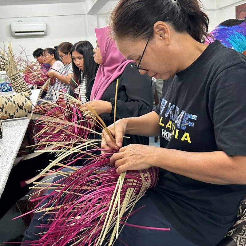 Group of rural artisans participating in a handicraft workshop, learning to weave handicrafts with rattan