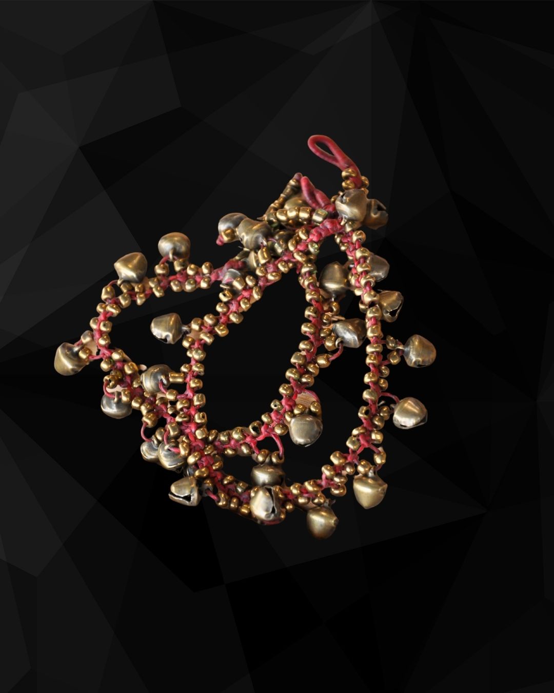 Red beaded anklets with gold beads and brass bells on a black geometric background
