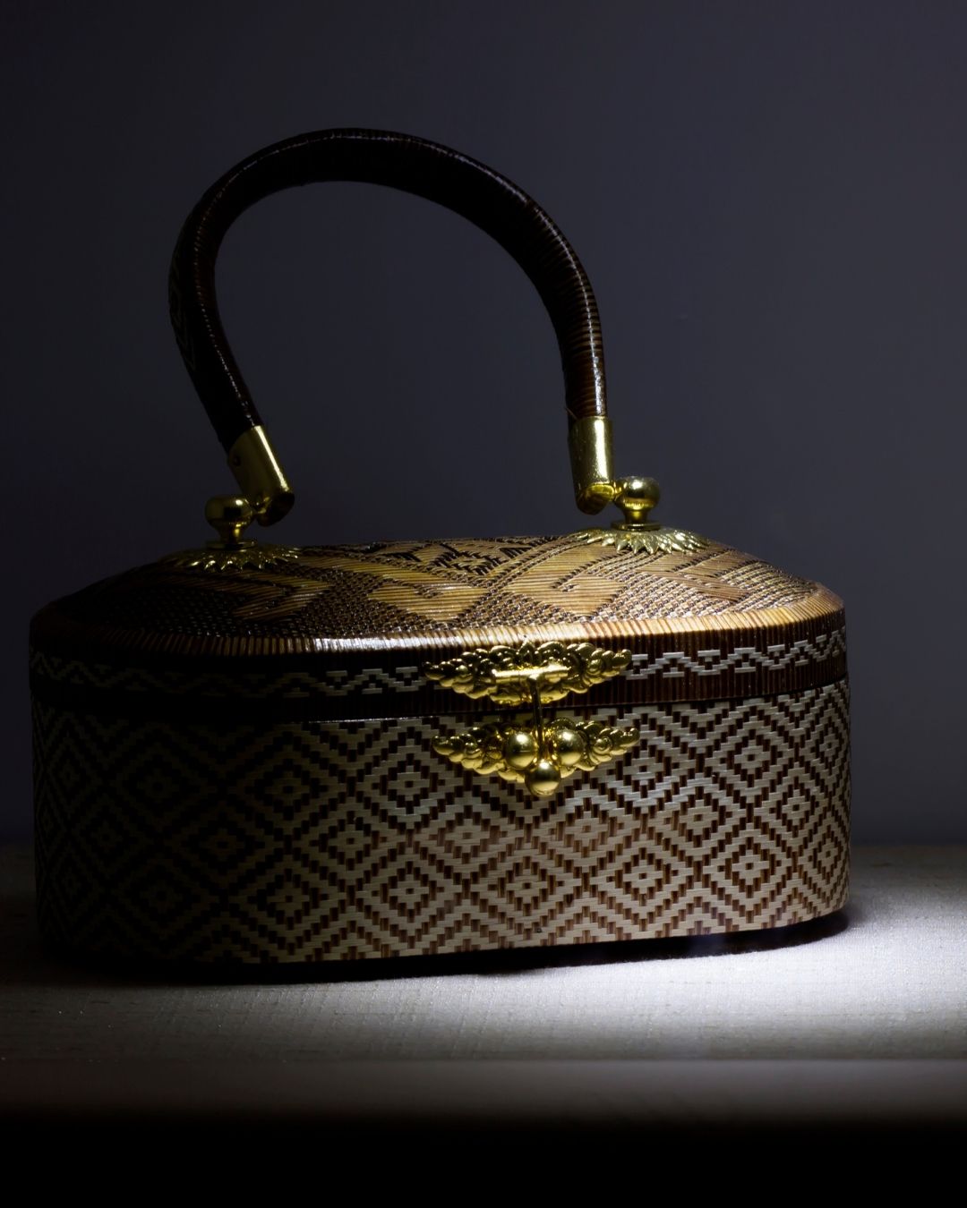 Classy Rattan Handbag with a gold plated lock on a dark background