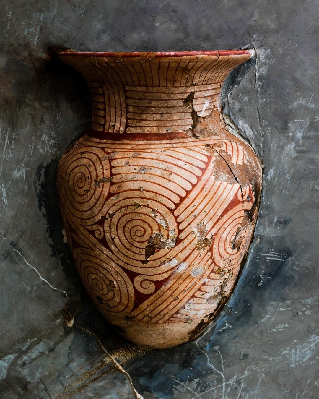 Decorative clay vase with spiral patterns on a textured gray background