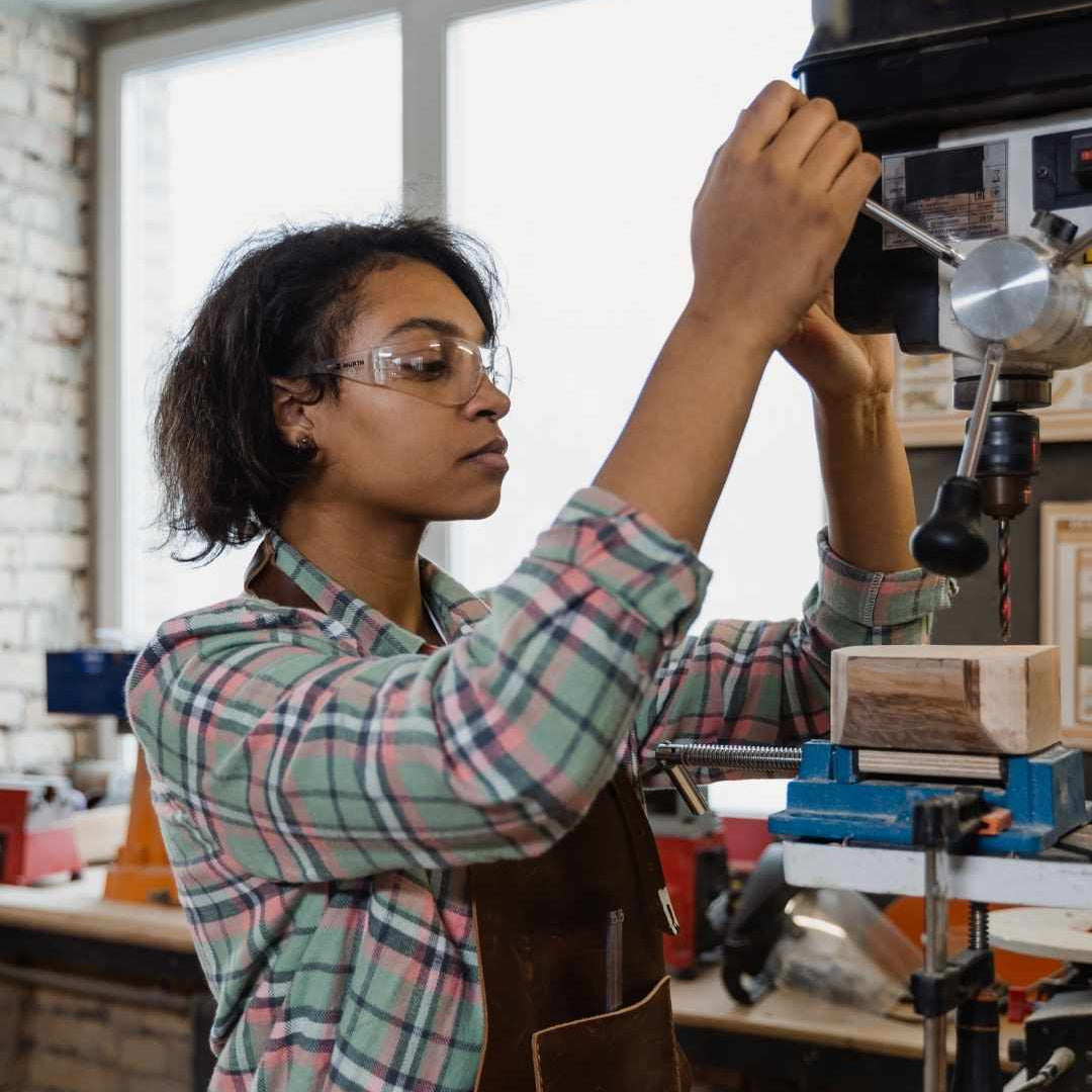 Person working with a drill press in a workshop