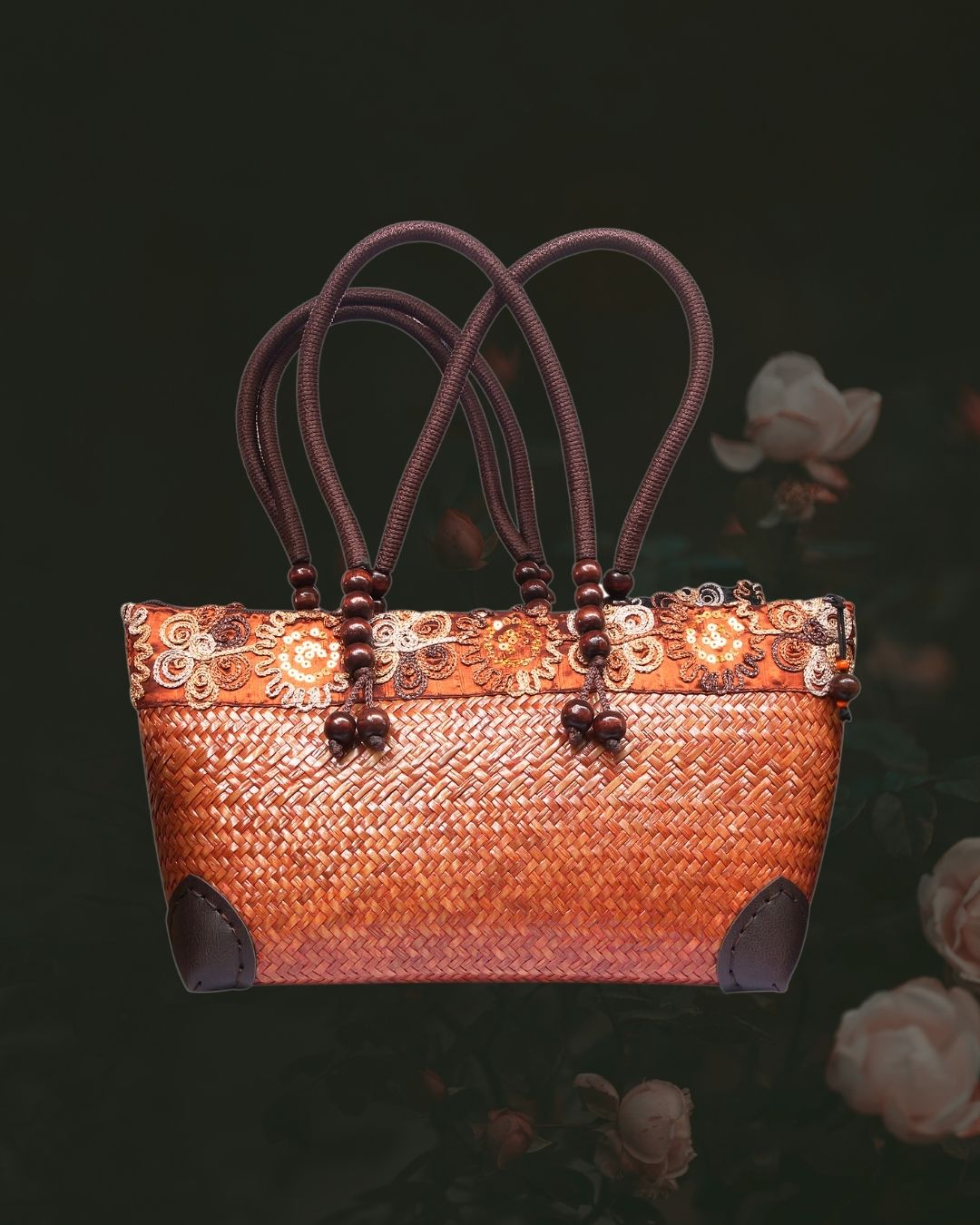 Woven handbag with floral patterns and brown handles on a dark background