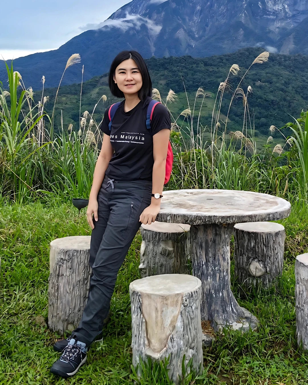 Person sitting at a wooden table in a mountainous landscape