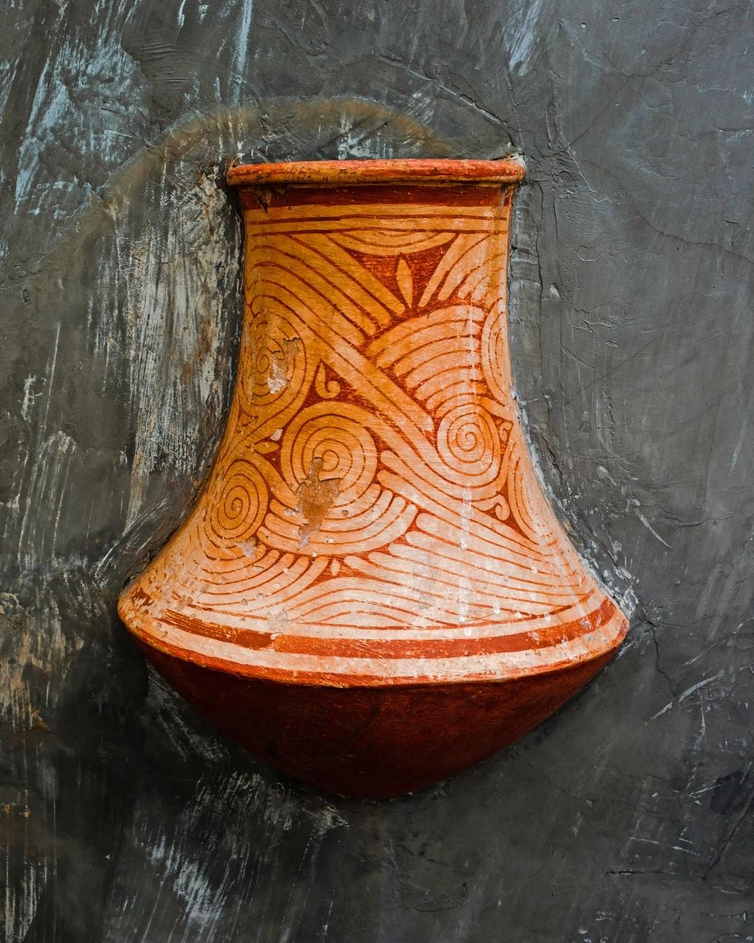 Clay vase with decorative patterns on a textured black background