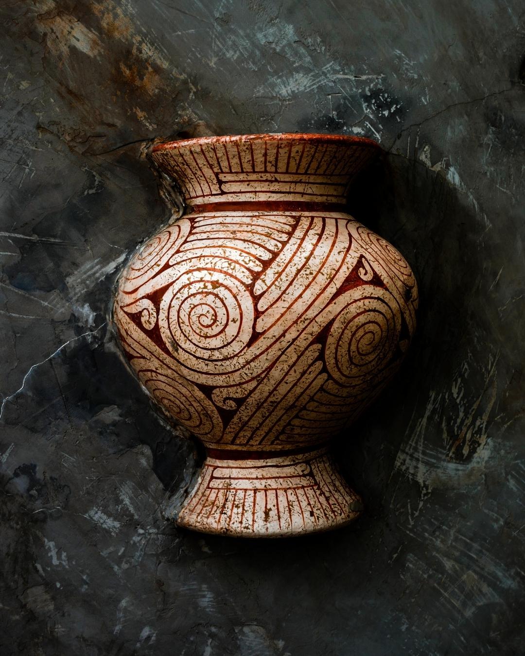 Ceramic vase with spiral patterns on a textured dark background
