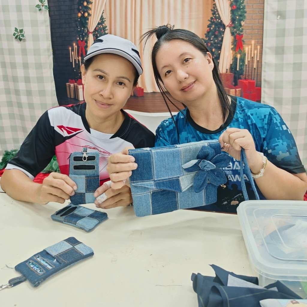 Two rural women proudly showcasing their handmade upcycled denim products