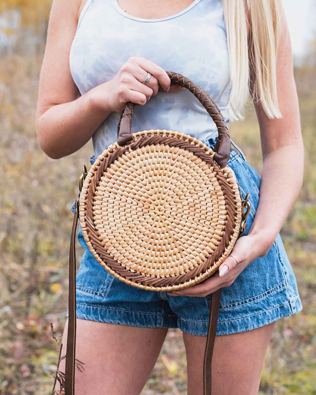 Person holding a round woven bag outdoors