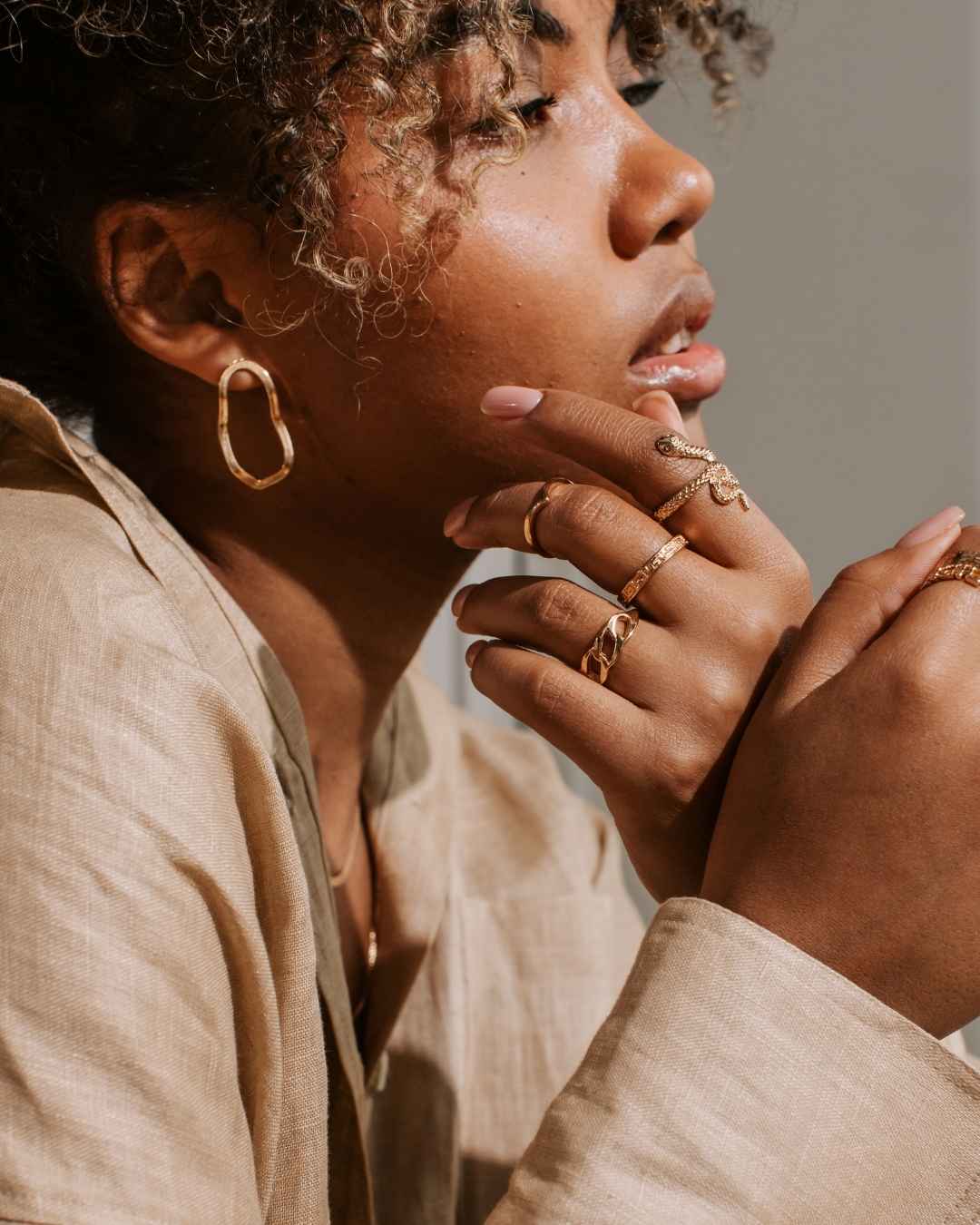 Woman wearing gold jewelry with a neutral background
