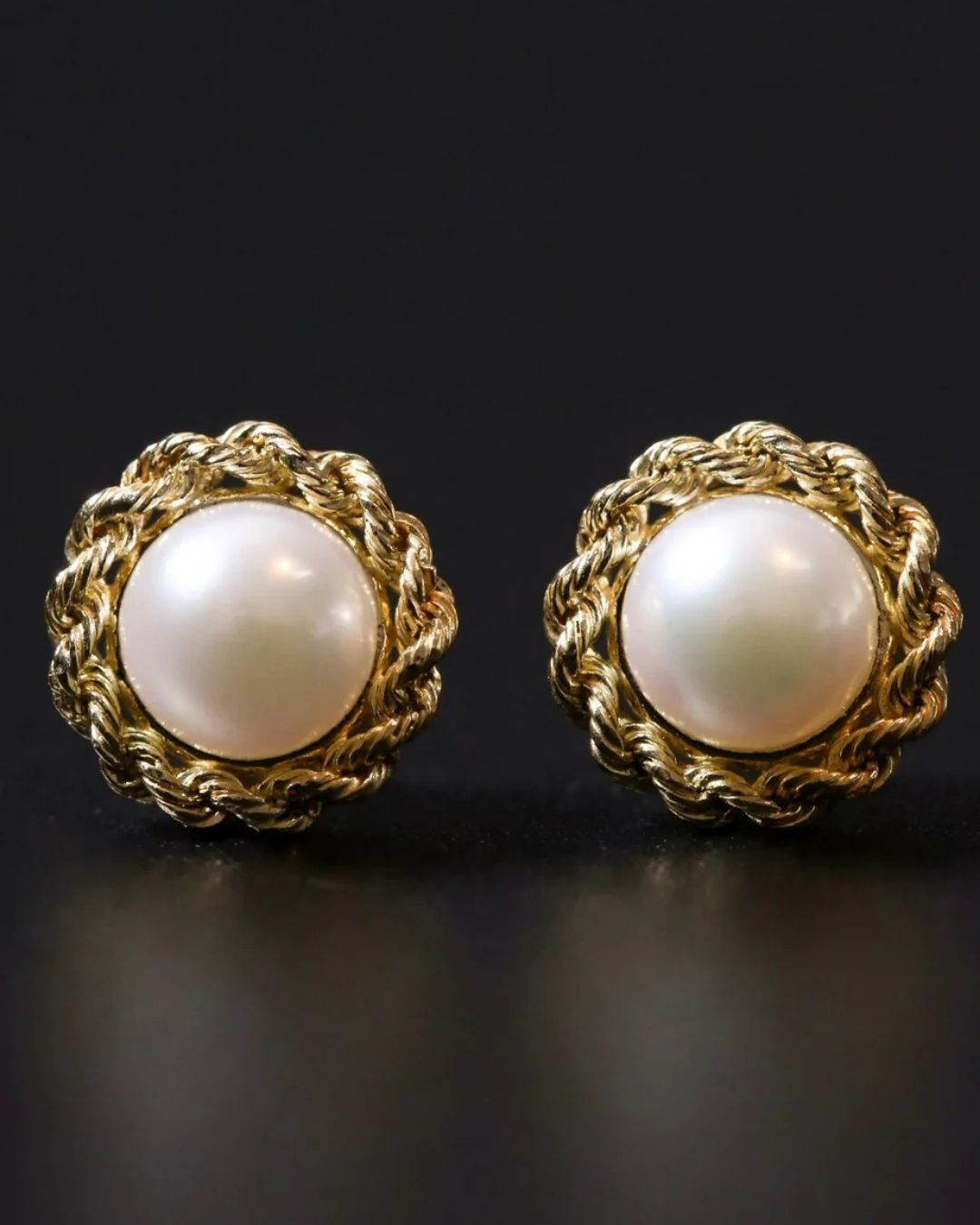 Pair of pearl earrings with gold settings on a dark background