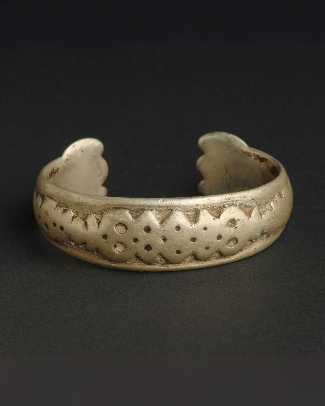 Brass bracelet with intricate design on a dark background