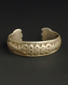 Brass bracelet with intricate design on a dark background