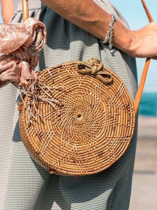 Round woven bag held by a person with a blurred background