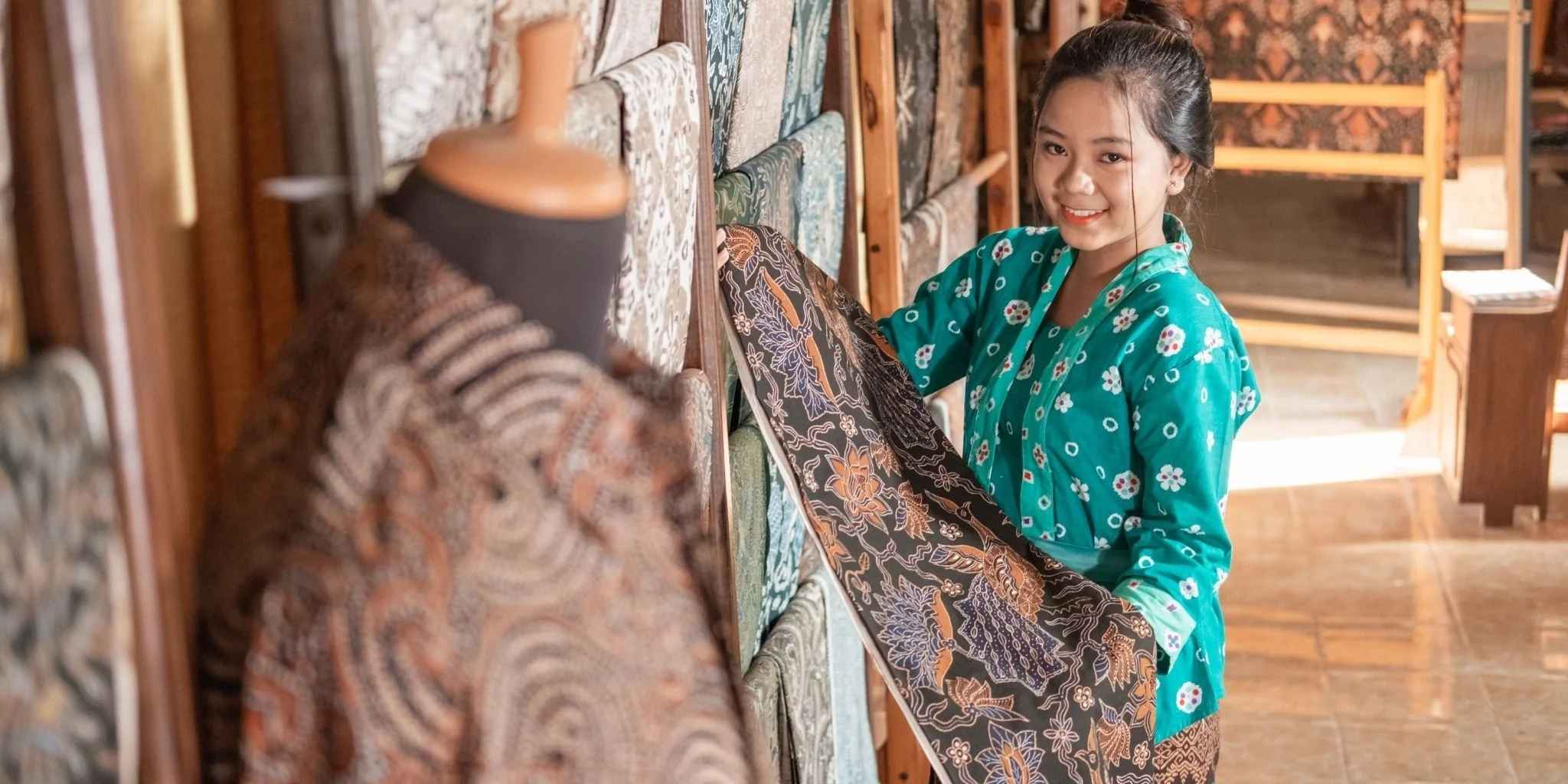 Woman holding a piece of patterned fabric in a traditional setting