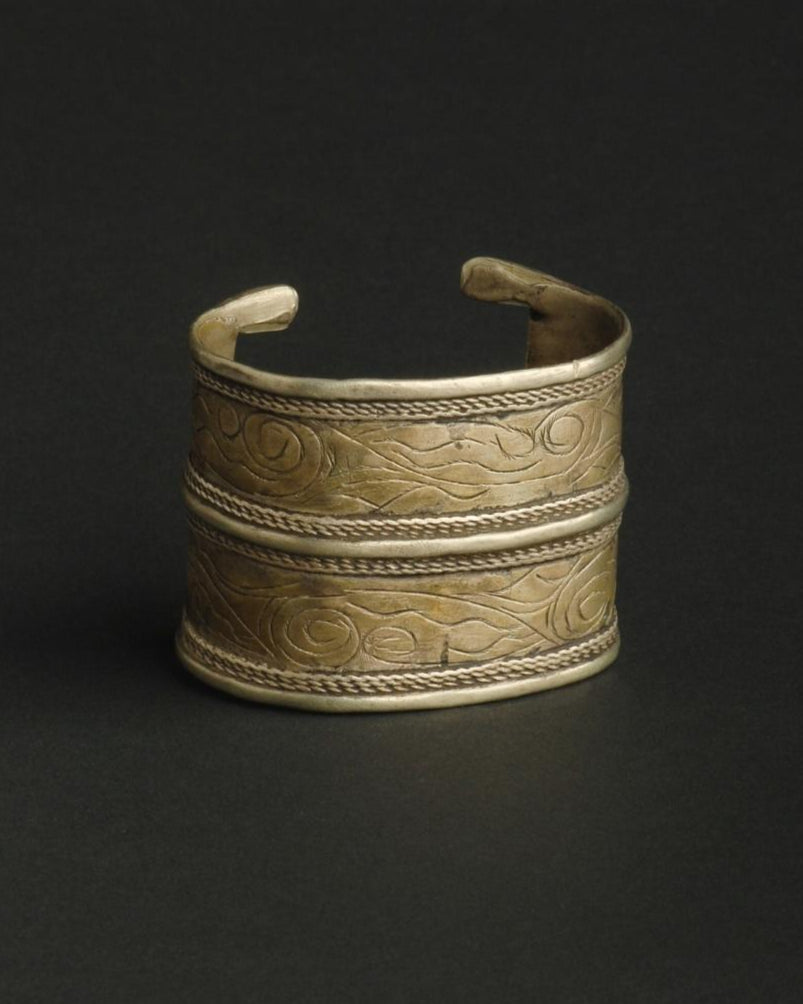 Brass bracelet with intricate designs on a black background