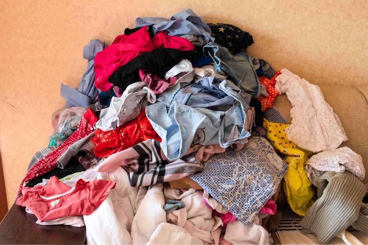 Pile of unwanted clothing on a wooden surface with a beige background