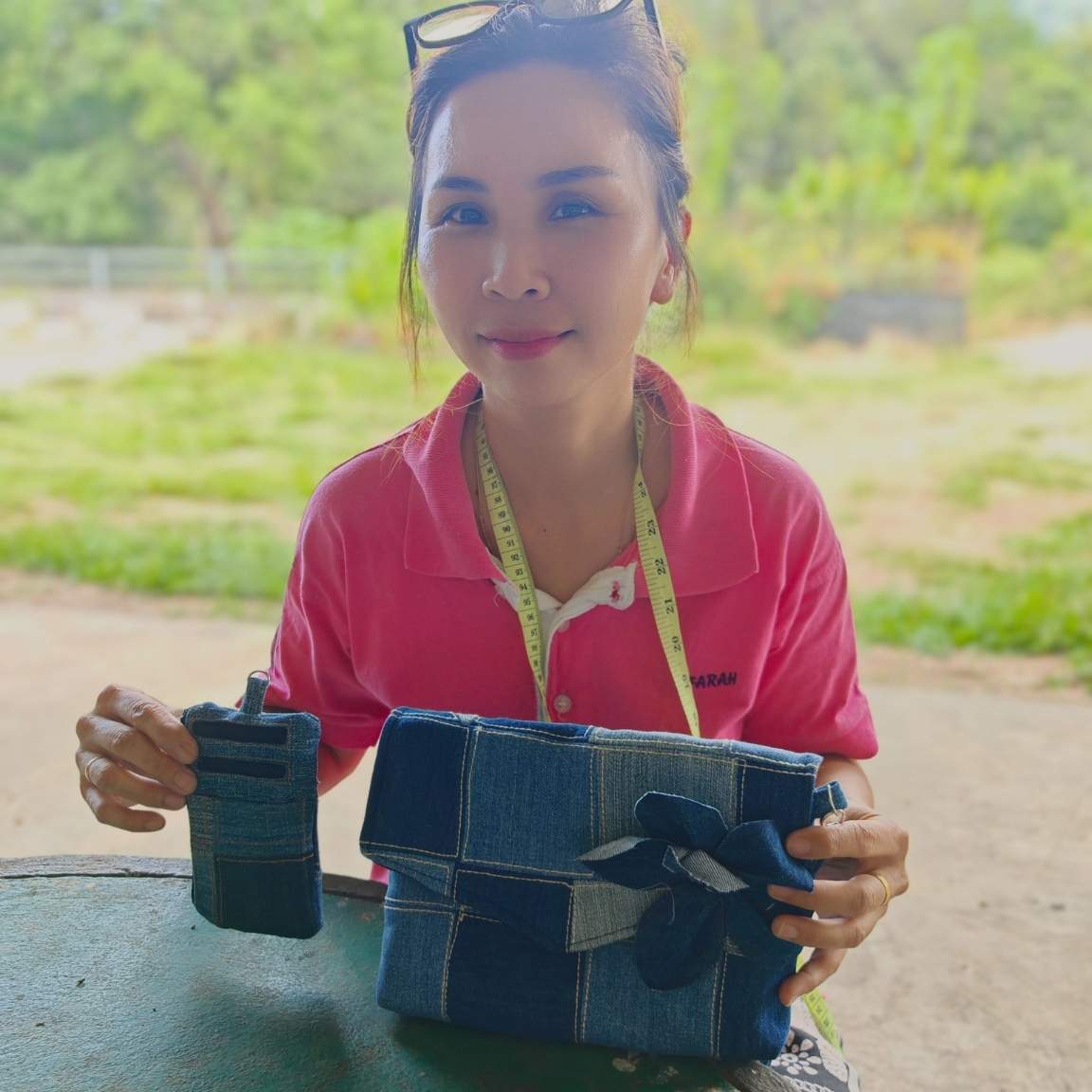 Woman holding a handmade blue denim envelope bag and card holder.
