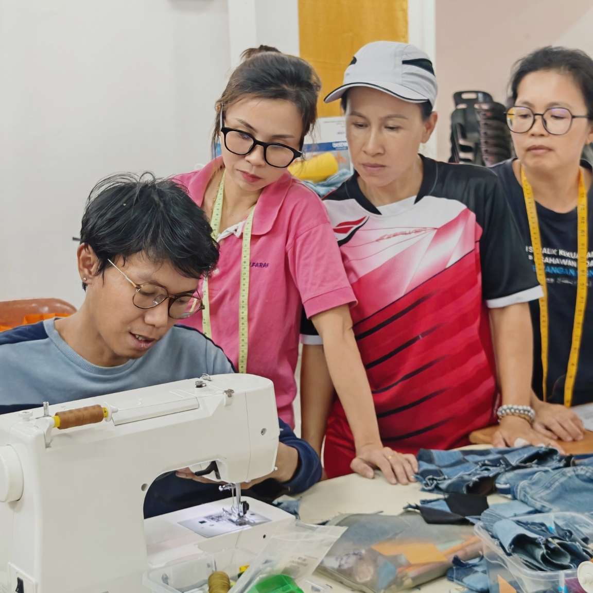 rural women attentively learning sewing techniques taught by the in house designer.