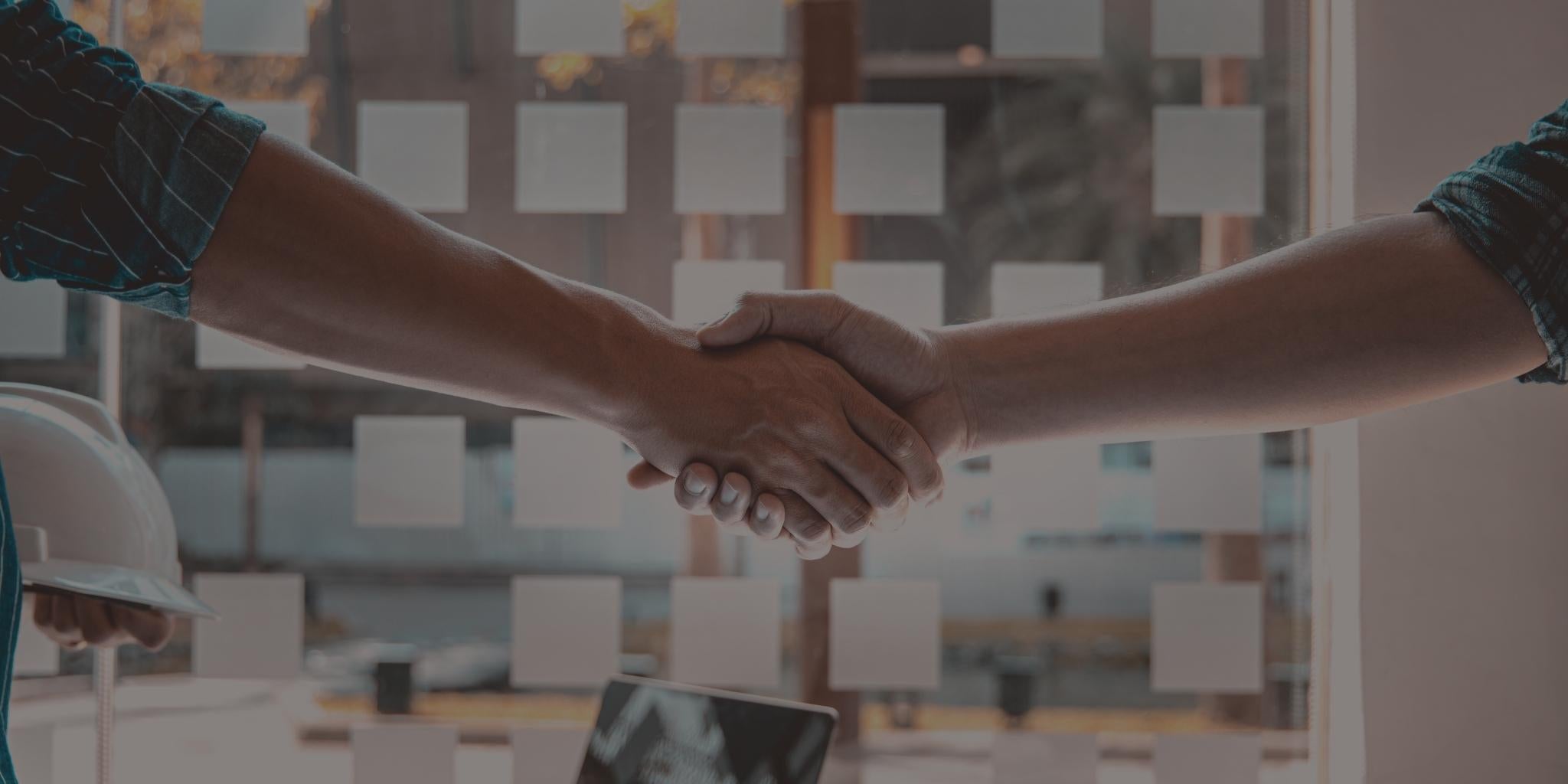 Two people shaking hands with a blurred office background