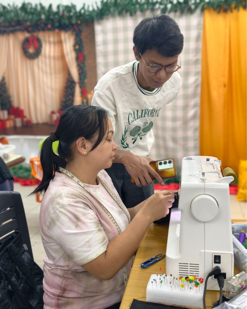 Trainer teaching the rural woman how to sew nicely