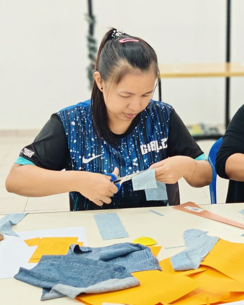 Person cutting fabric with scissors at a table
