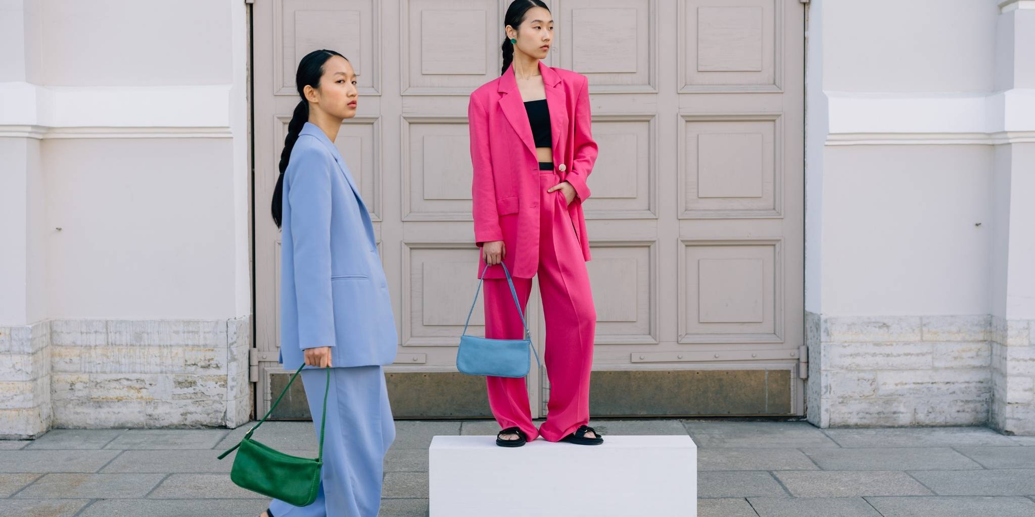 Two women in stylish outfits standing in front of a building.