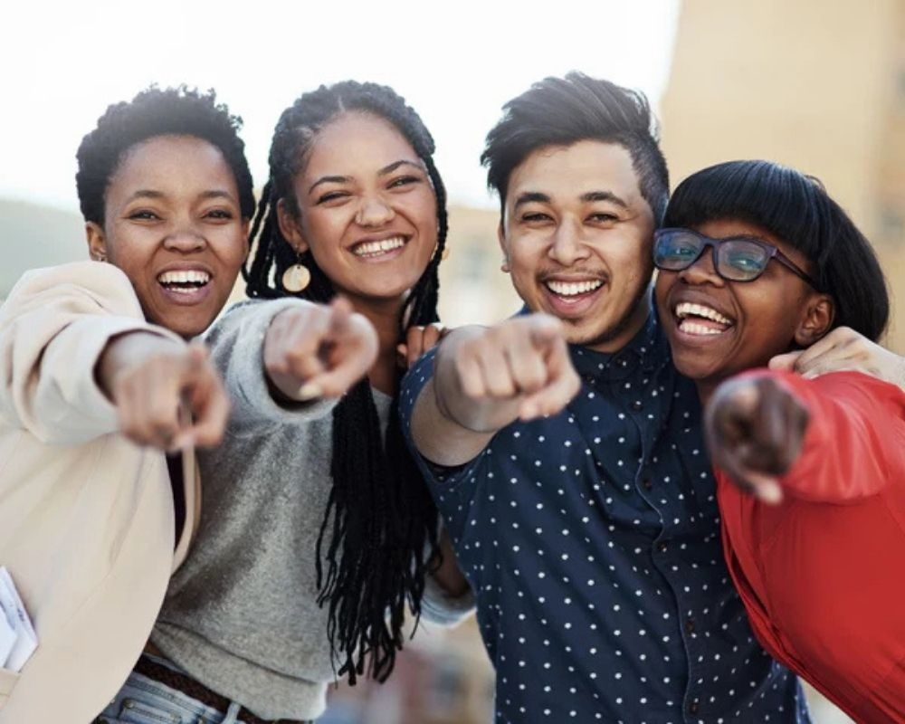 Four friends pointing forward with a blurred background