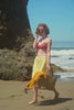 woman walking along the beach while carrying a rattan bag