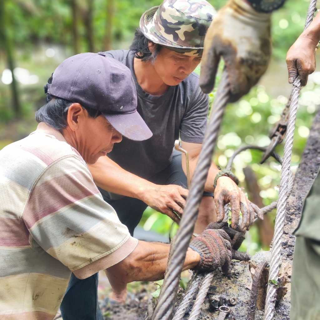 Two rural villagers working to fix their broken community suspension bridge