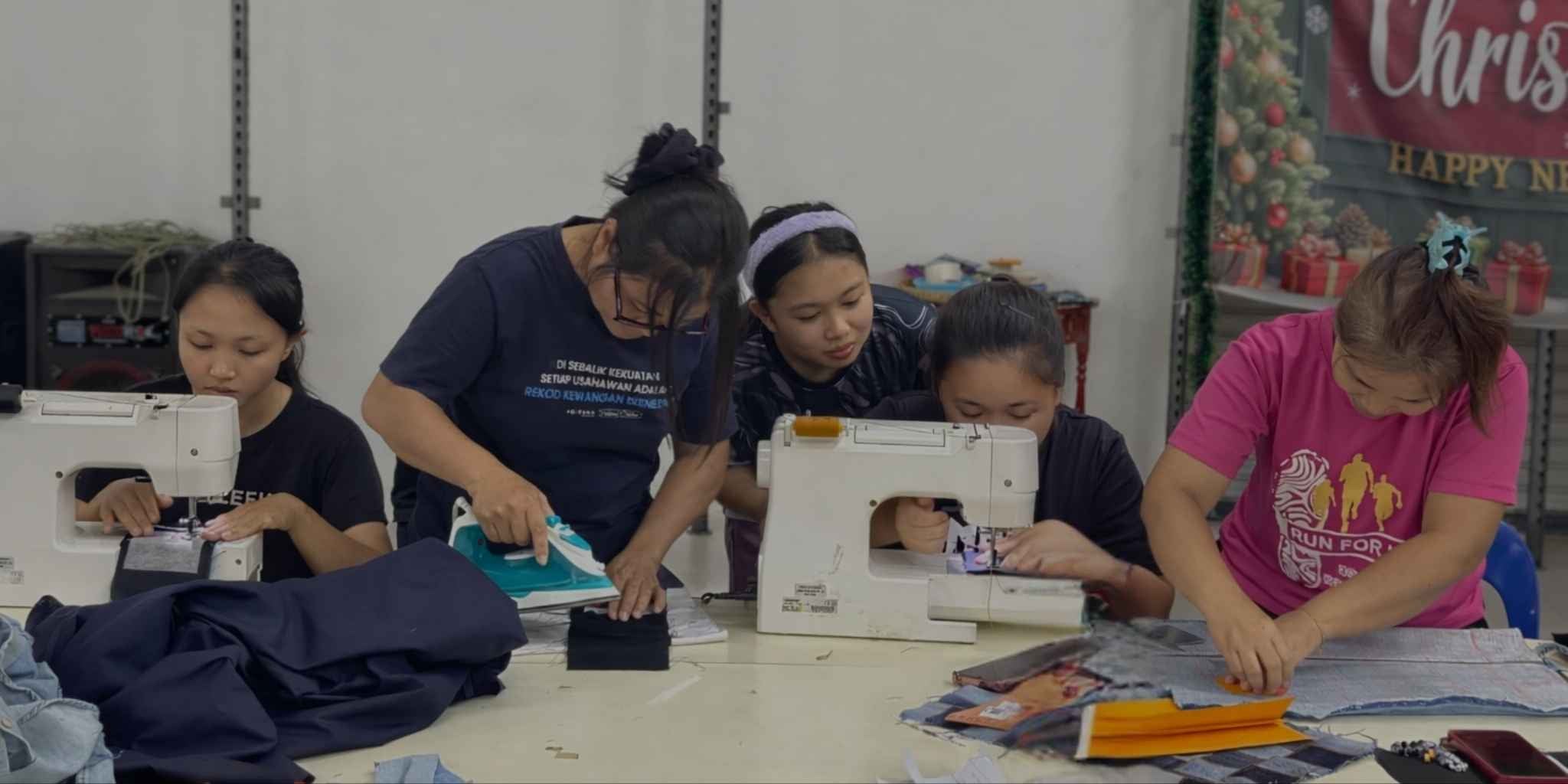 Group of women working on sewing machines in a workshop setting.